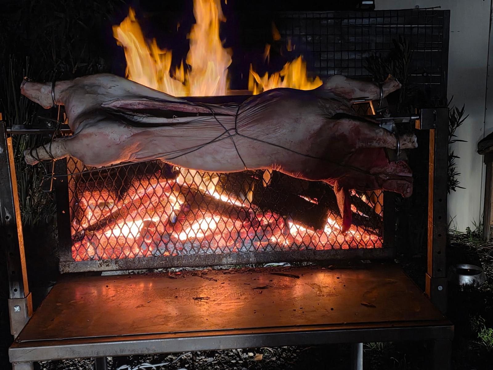 Agneau entier à la broche sur braises rougeoyantes, méchoui au feu de bois dans le Gard
