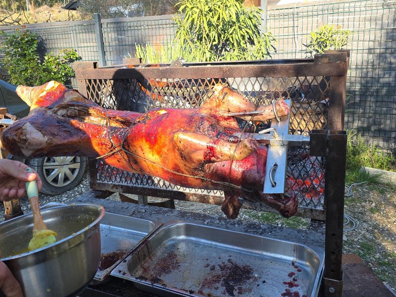 Arrosage du cochon avec ses sucs pendant la cuisson à la broche